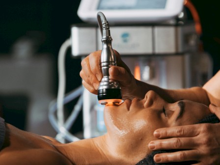 A person is receiving a facial treatment or skin therapy using a specialized device held by a practitioner.