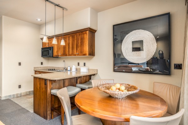 A modern kitchen with wooden cabinets, a round dining table, and a large abstract artwork on the wall, creating a cozy atmosphere.